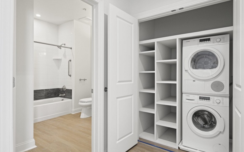 stacked washer/dryer units in laundry closet next to bathroom